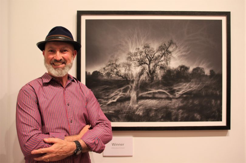 Mark Kelly standing next to his Goulburn Art Award winning photographic piece Ghosts of the Past.