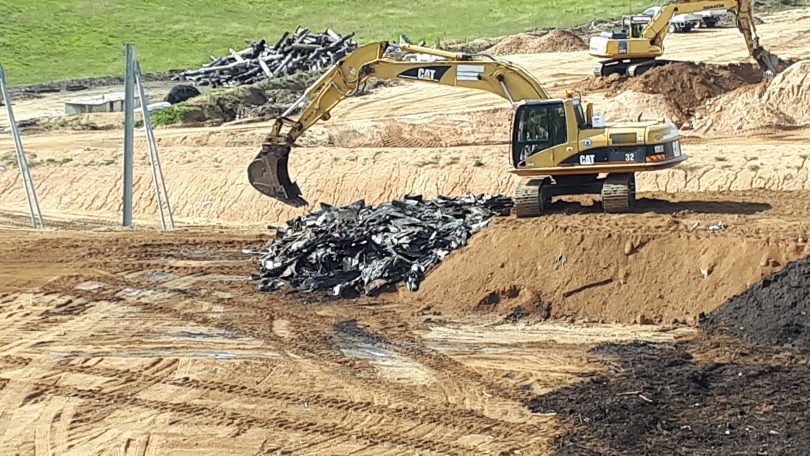Digging equipment dumps bushfire waste into landfill.