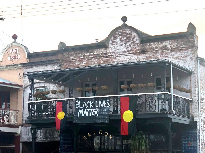"Black Lives Matter" banner and Aboriginal flags hang from balcony of Braidwood building.