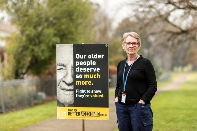 Kerry Kelly standing next to aged-care placard.