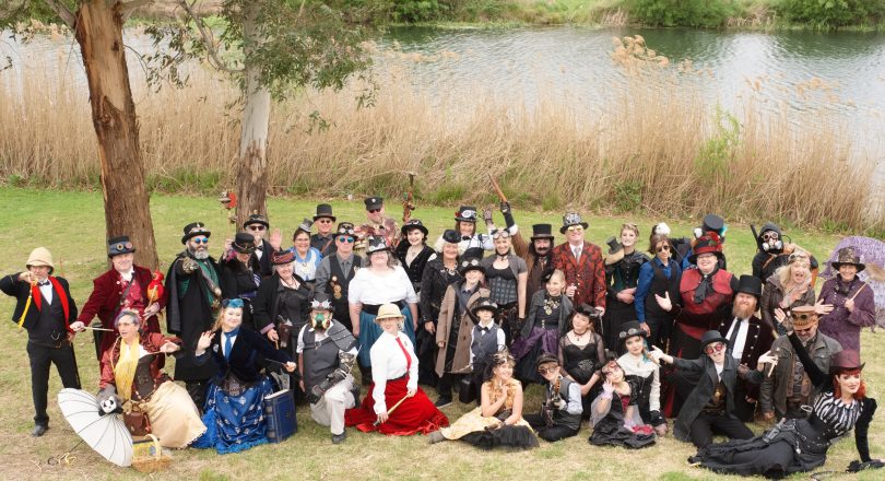 Group photo of Steampunk Victoriana Fair participants posing by riverbank.