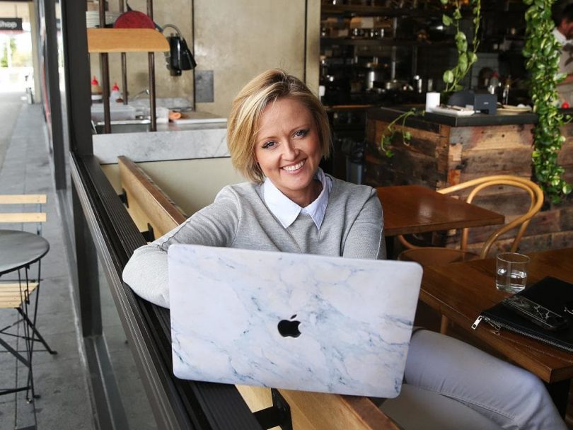 Jen Hollingsworth sitting at laptop in cafe.