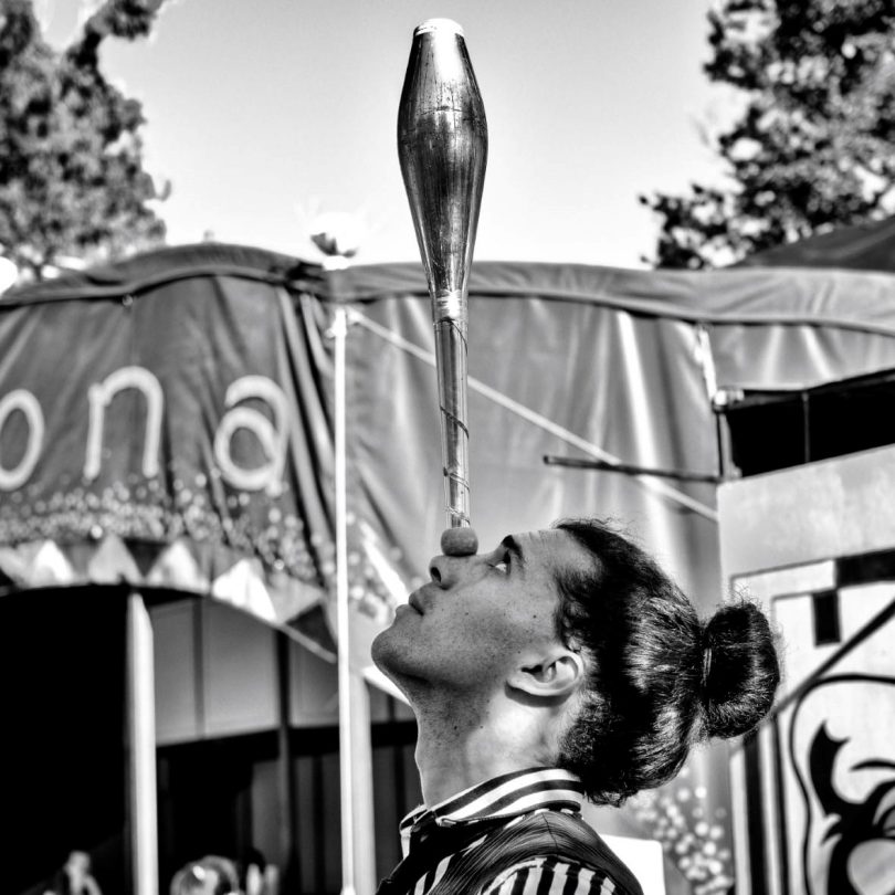 Circus and street performer Rhys Davies balancing juggling club on nose.