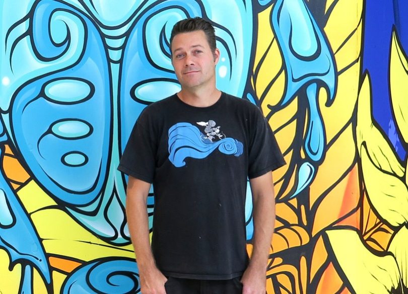 Artist Tim de Haan (aka 'Phibs') standing in front of mural.