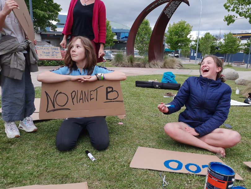 Harry Haggar and Alina North-Andrew making climate-action signs on grass.