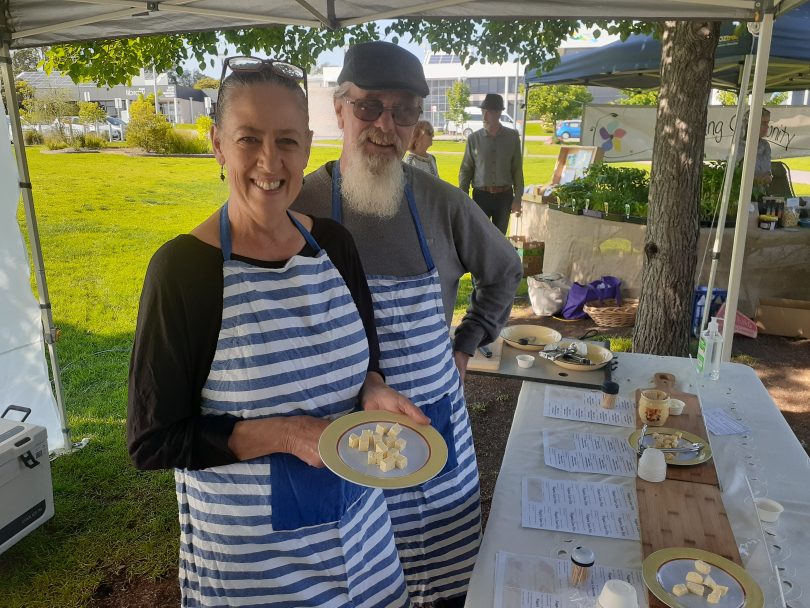 Lisa Kremmer and Wayne White holding cheese at their Bega Farmers Market stall.