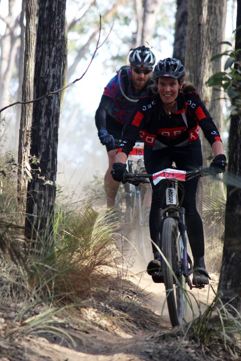 Woman and man mountain biking in bush.