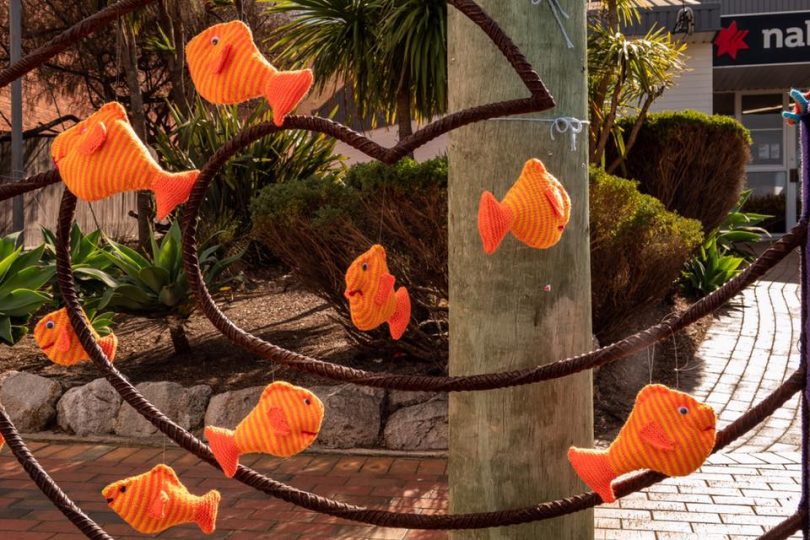 Knitted fish hanging in streetscape display.