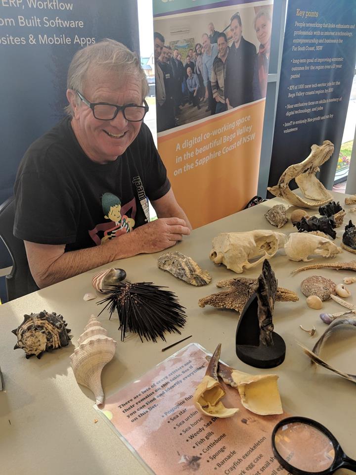 Paul Whittock sitting at table with sea shells display.
