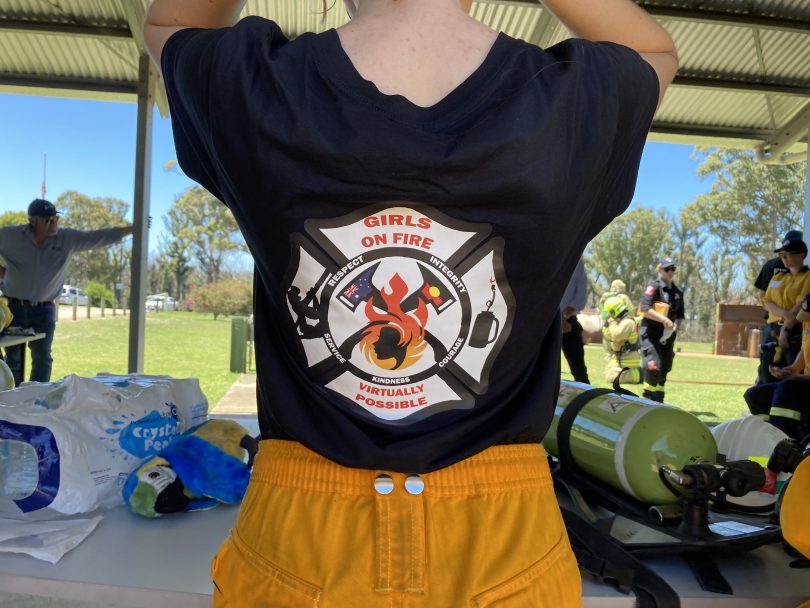 Girl showing Girls on Fire logo on back of T-shirt.