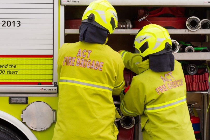 Two ACT firefighters in uniform, getting equipment from a truck