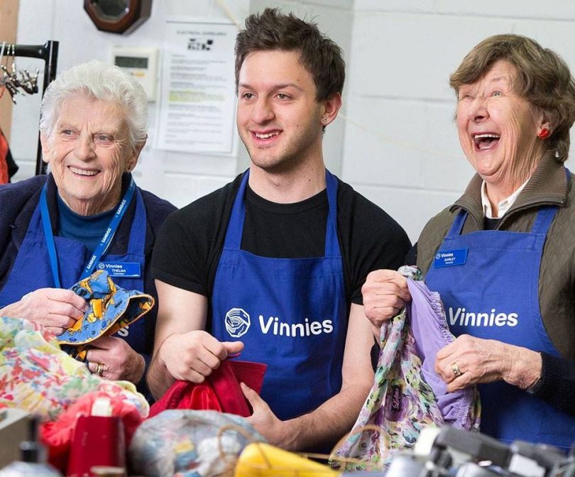 Three Vinnies workers holding donated items.