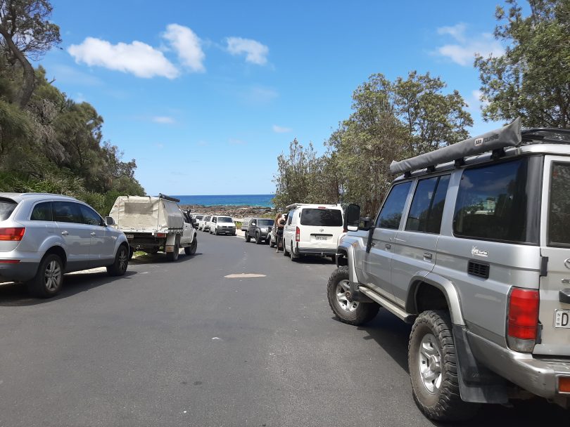 Cars parked on side of road at South Broulee Beach.