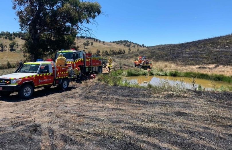 Fire trucks by a dam, surrounded by burnt paddocks