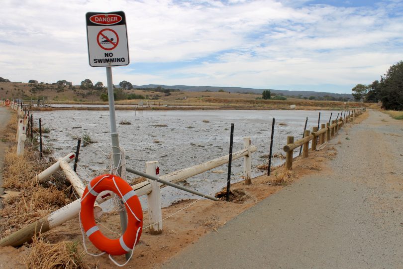 Triangular sludge ponds at a sewage treatment plant, with a ''No Swimming'' sign.