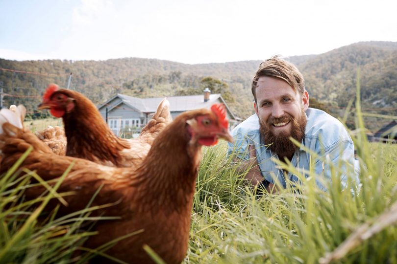 Paul West on farm with chickens.