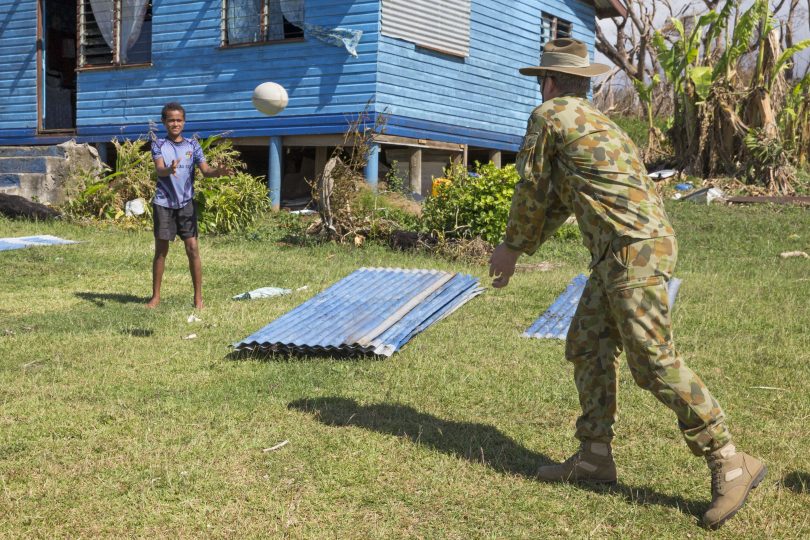 James Dugdell passing rugby ball to local girl in Fiji.