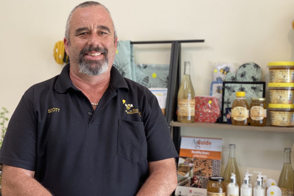 a man standing in front of a display of honey products for sale in a shop