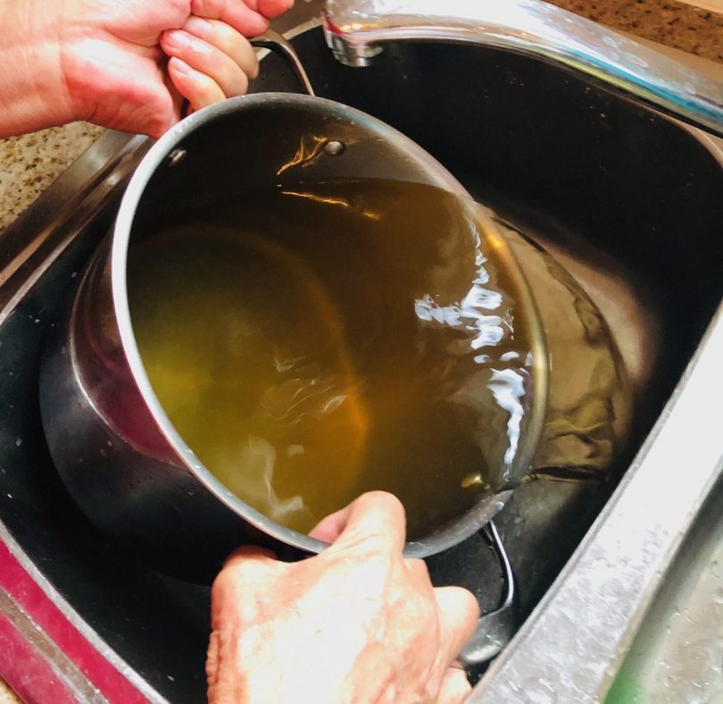 Yass resident Tom O’Dea shows the brown water that pours from his taps.