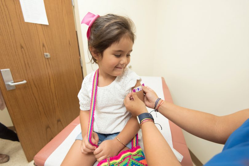 A young girl receiving an injection from nurse.