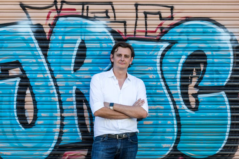 Anton Szpitalak standing in front of graffiti wall