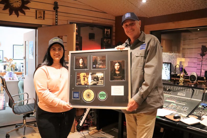 Mariah K and Stephen Lindsay holding framed album artwork in studio