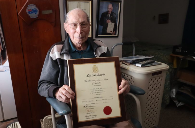 Lance Cooke holding framed certificate at home in Gunning