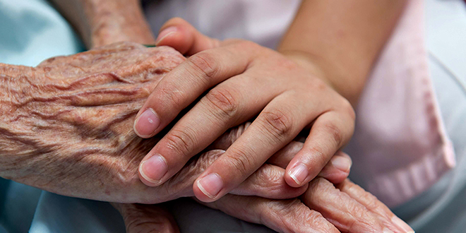 One hand holding elderly person's hands