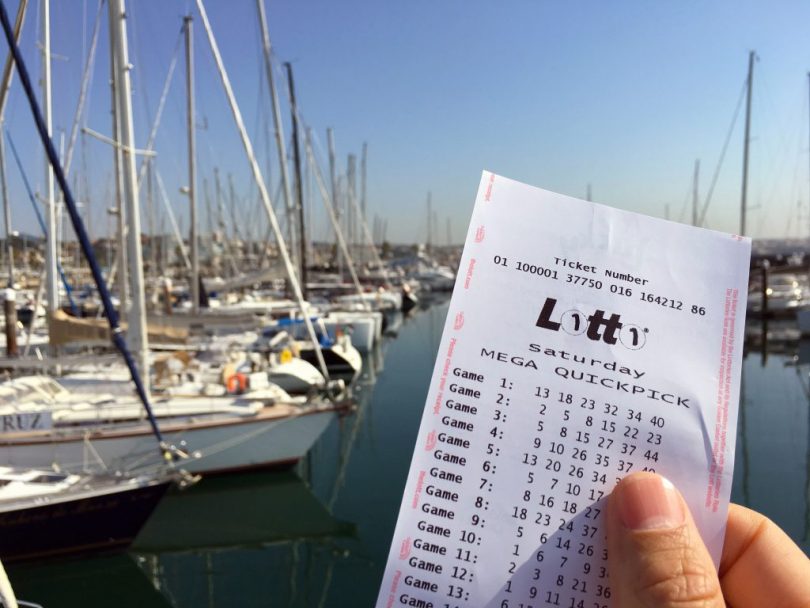 Hand holding Lotto ticket with boats in background