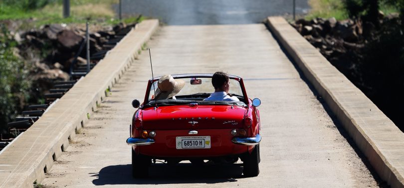 Classic convertible sports car driving across bridge