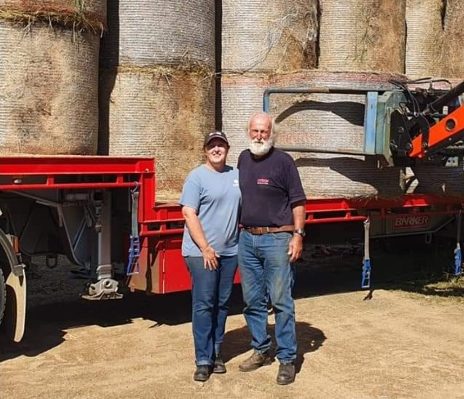 Tracia Milton and Peter Bowie standing next to hay bales on truck
