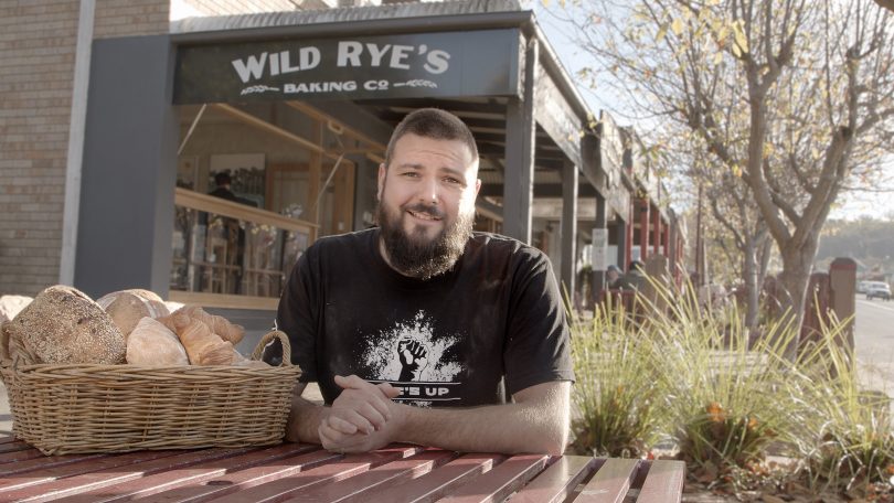 Matt Crossley sitting outside Wild Rye's bakery in Pambula with basket of bread