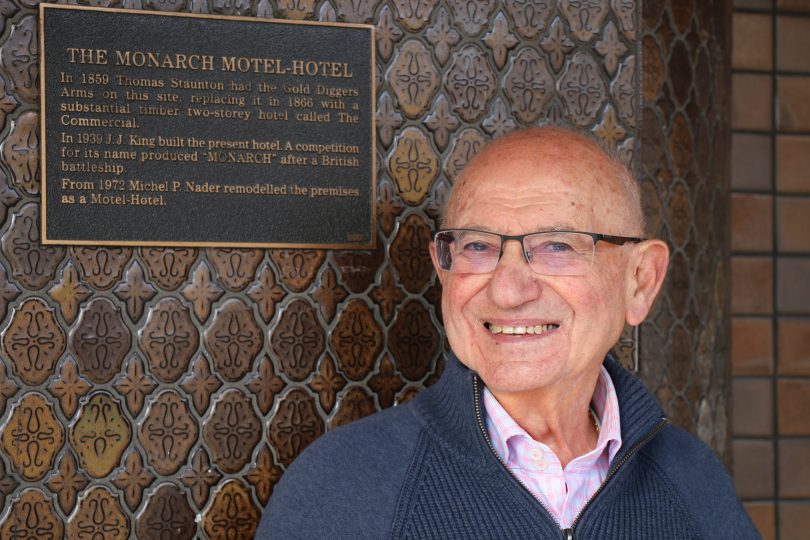 Michel Nader next to plaque at Monarch Hotel in Moruya