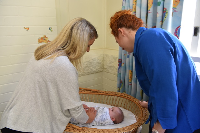 two ladies look over a baby in bed