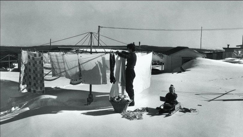Historical photo of woman hanging washing in snow in Cabramurra