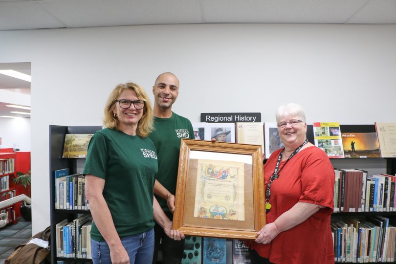 Three people with framed certificate