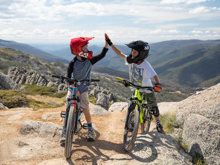 Two boys high-fiving on mountain bikes