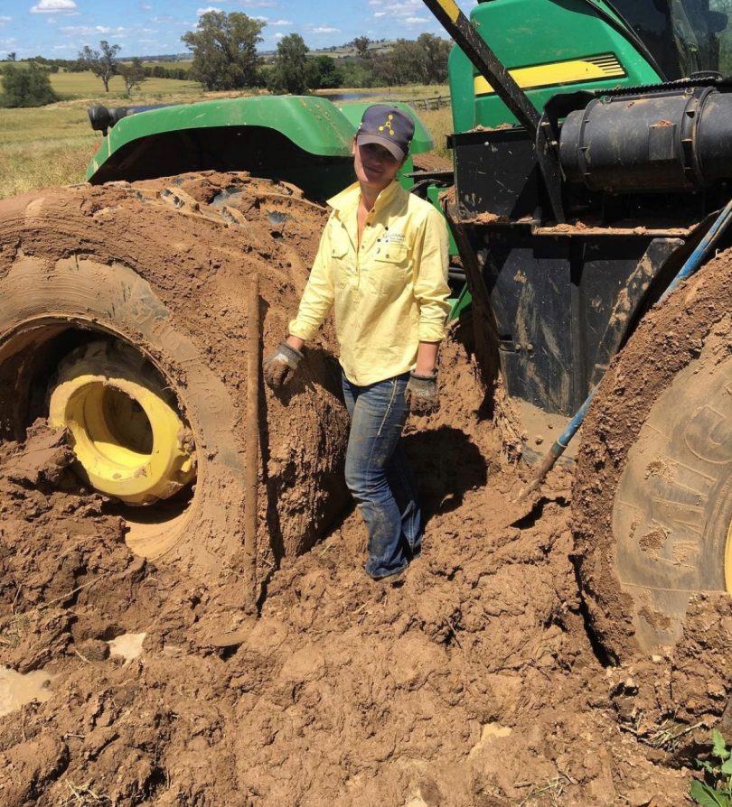 Lucy Hayes standing in mud with bogged tractor