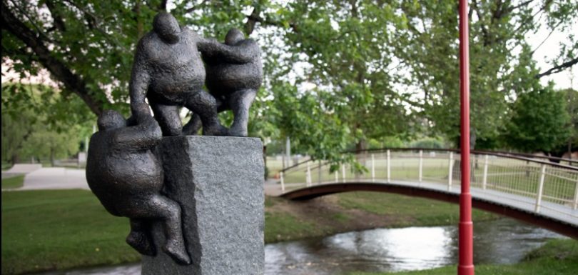 Sculpture of humanoid figures climbing a plinth