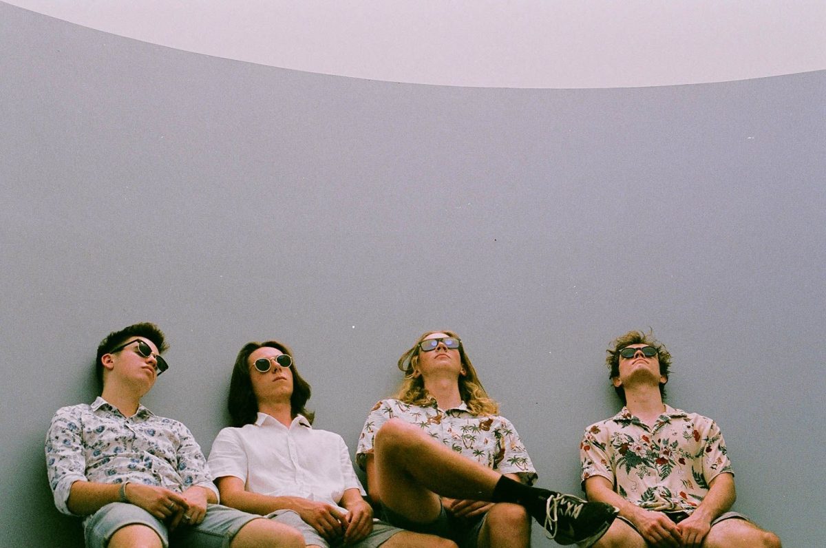 The four members of Canberra indie-rock band Flowermarket in sunglasses sitting on chairs
