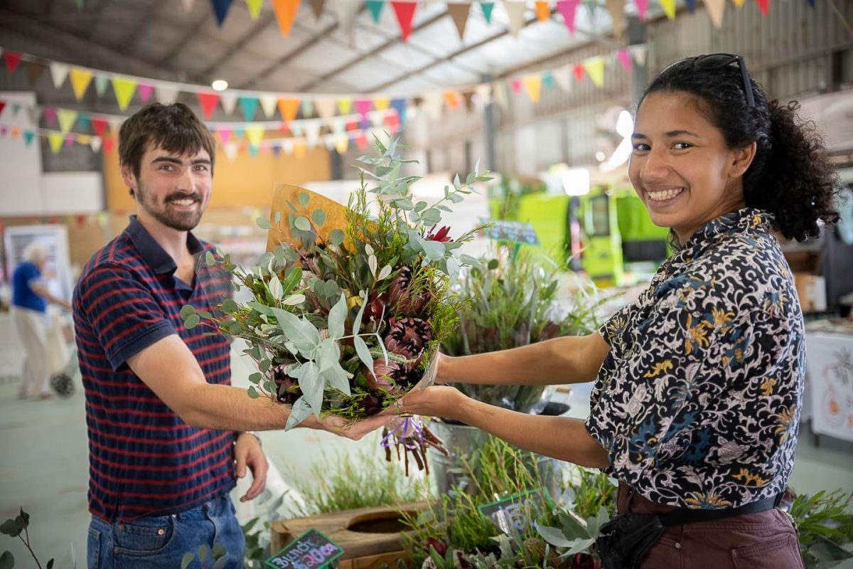 Women hands over a bouquet of flowers to a man at the Wagga Wagga Showground Markets