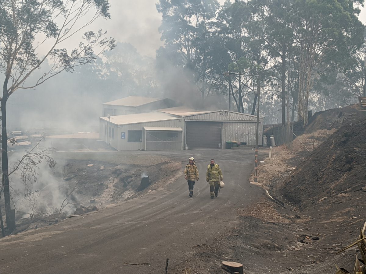 Two firemen walking through bushfire smoke