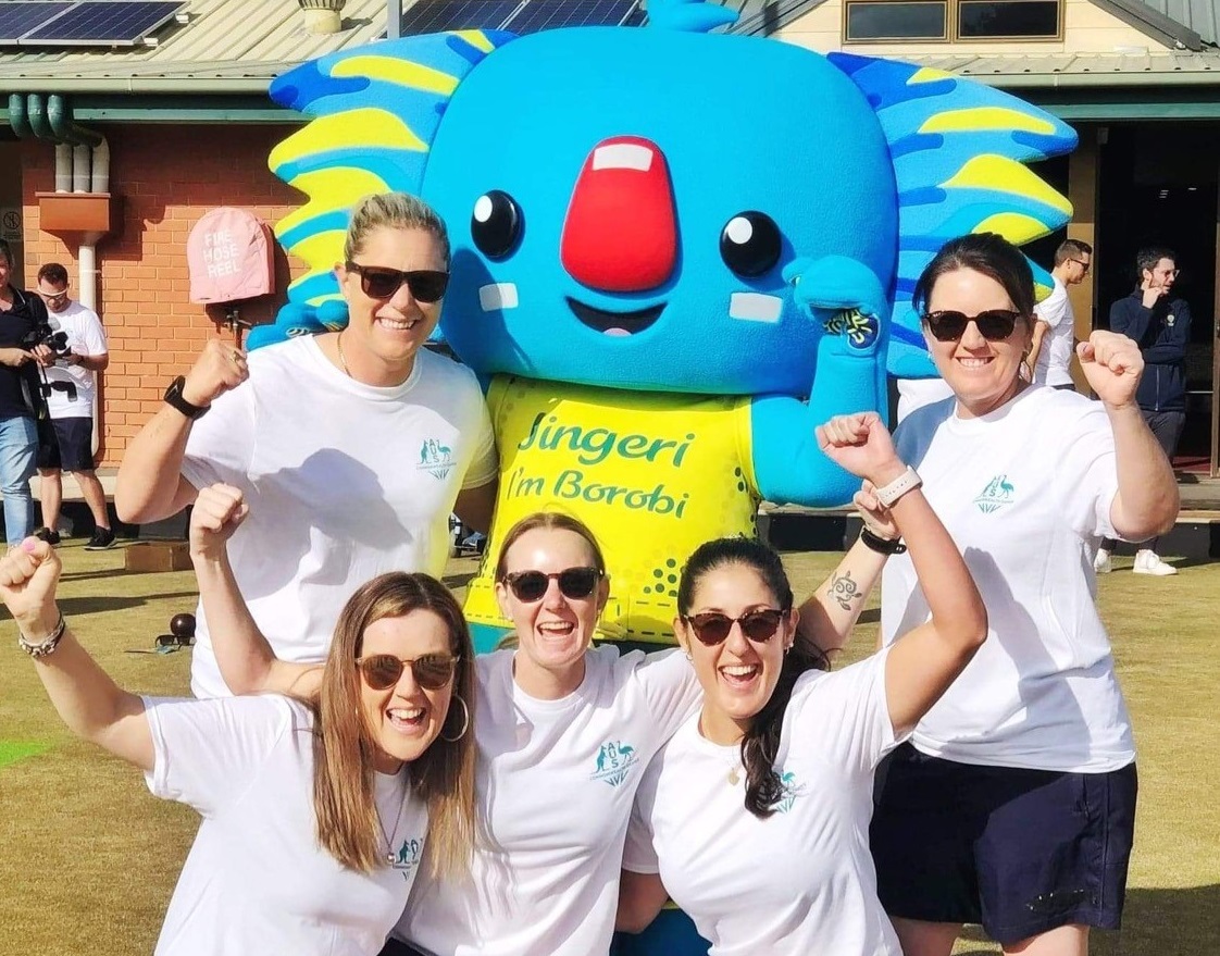 Five members of the women's Australian Jackaroos lawn bowls team cheer with the koala mascot