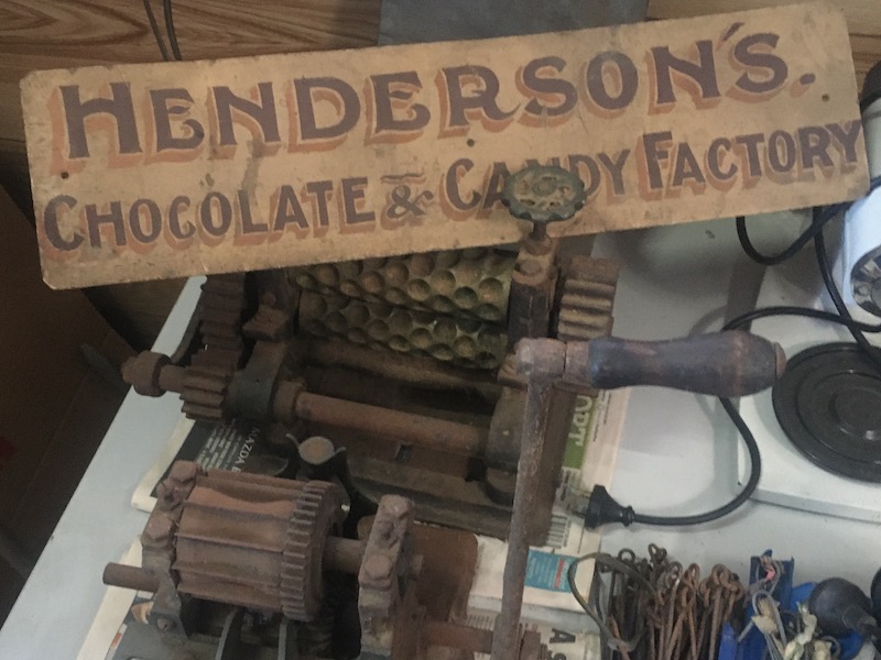 Old sign that reads Henderson's Chocolate and Candy factory and an old rusted chocolate machine