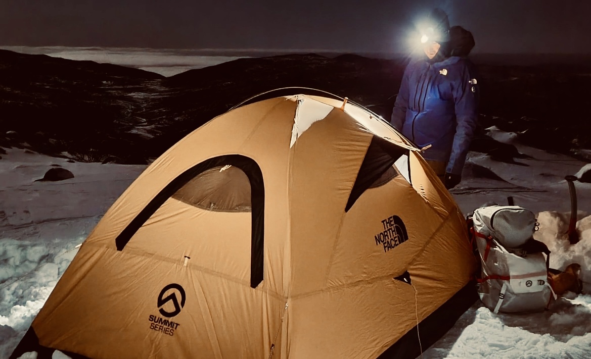 Man next to a tent in the snow