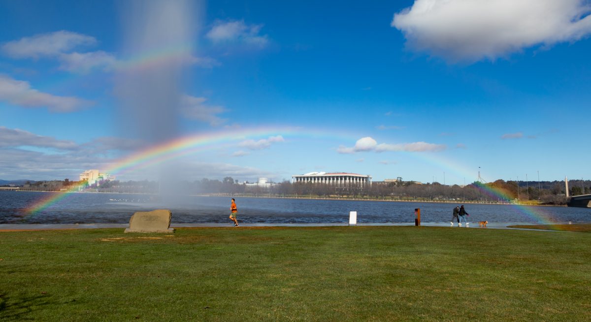 Walkers and runner under a rainbow by Lake Burley Griffin.