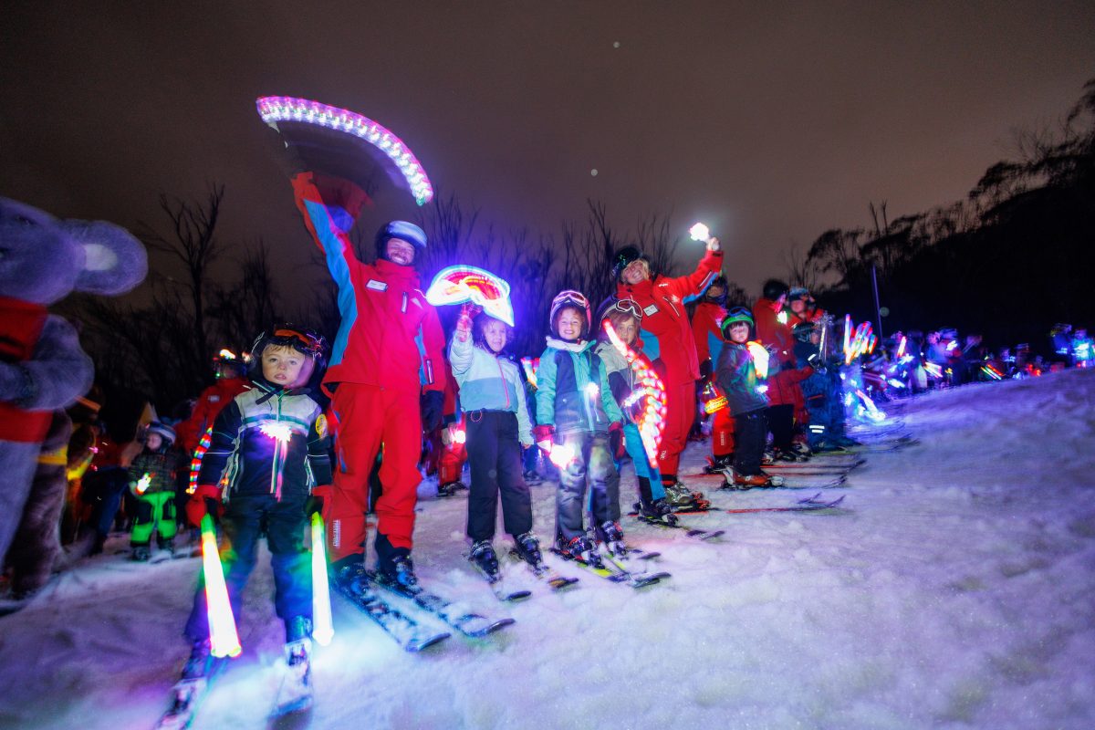 Kids and instructors lining up on the snow with flares at night