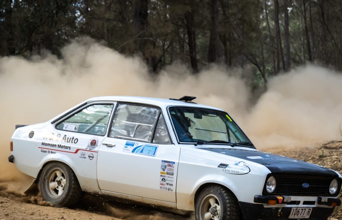 Race car throwing up dirt in a forrest setting