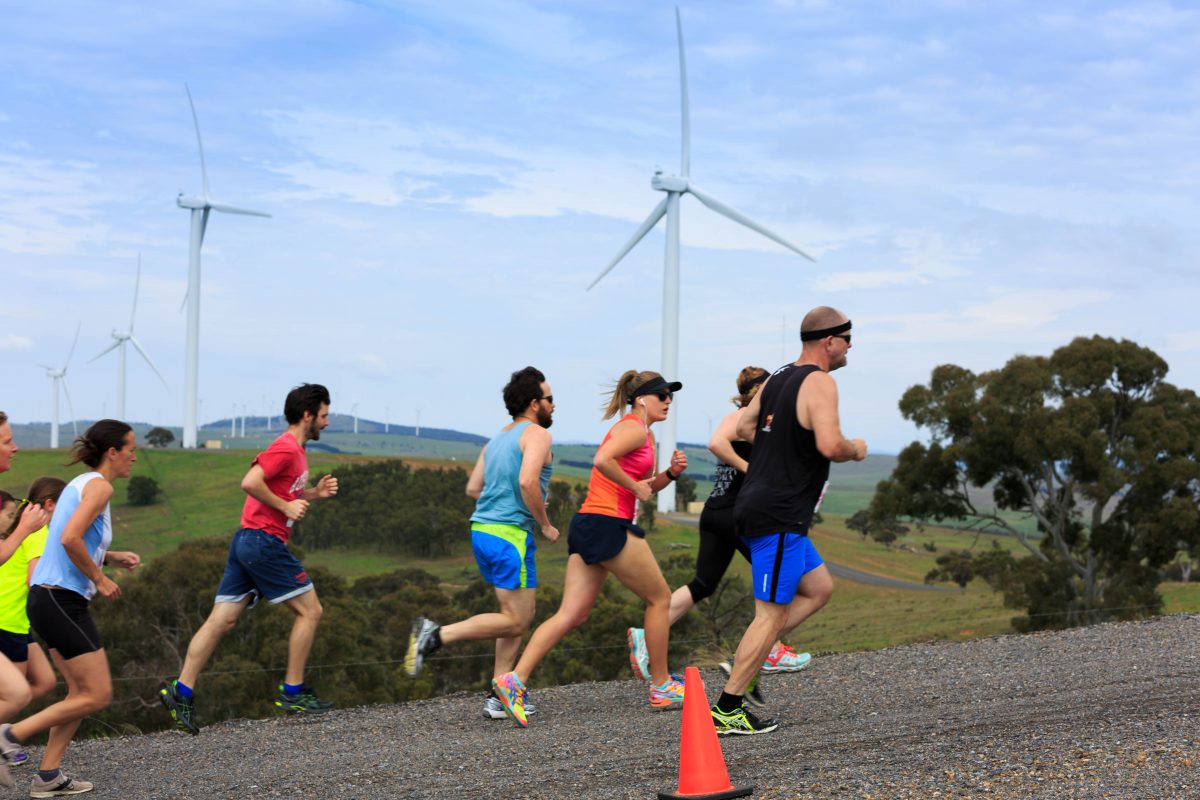 People running with wind turbines in the background
