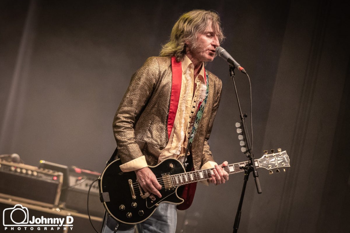 Musician Tim Rogers on stage singing and playing guitar